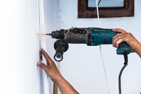 close up of electric drill making hole in a wall: repair, building and home conceptの写真素材