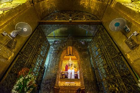 MANDALAY, MYANMAR - JUL 17, 2018 : Senior monk wash the face of Mahamuni Buddha image at Mahamuni temple. the most highly revered Buddha image in the country.のeditorial素材