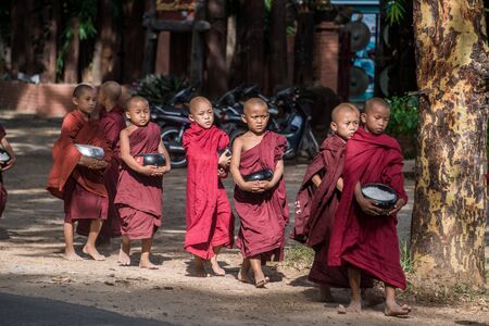 BAGAN, MYANMAR - JUL 18, 2018: Buddhist novices walk to collect alms and offerings along the road at...
