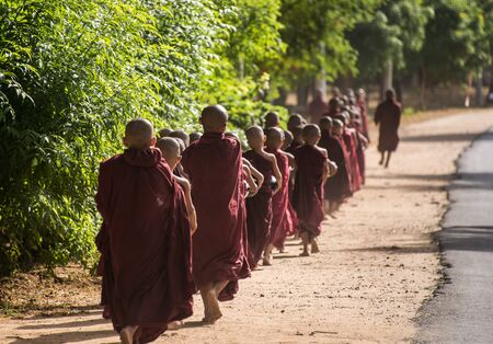 BAGAN, MYANMAR - JUL 18, 2018: Buddhist novices walk to collect alms and offerings along the road at...