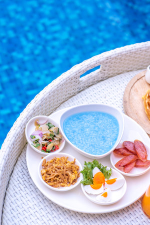 Breakfast in swimming pool, floating breakfast in villa resort. relaxing in calm pool water, healthy breakfast and tropical fruit.の写真素材