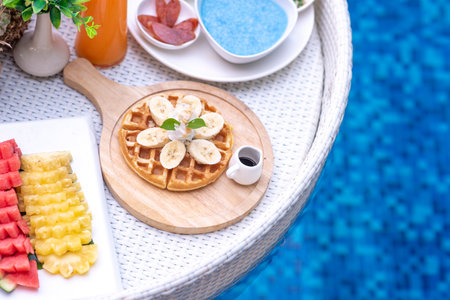 Breakfast in swimming pool, floating breakfast in villa resort. relaxing in calm pool water, healthy breakfast and tropical fruit.の写真素材