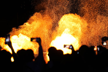 silhouette of crowd taking photo with phone of fire in background