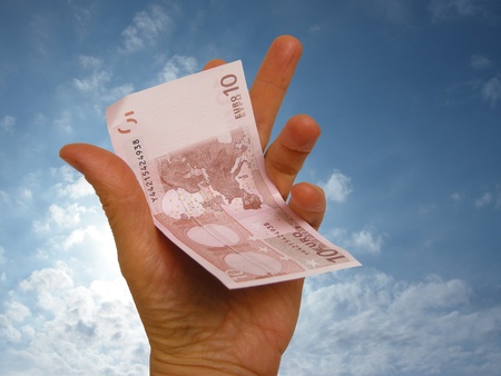 hand holding paper money on blue sky backgroundの写真素材