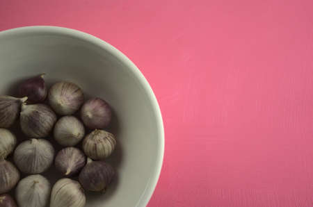 Garlic in bowl on acrylic scratchy pink canvas background. Food, kitchen, eating, still life photography with copy space.の写真素材