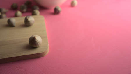 Garlic on cutting board on acrylic scratchy pink canvas background. Food, kitchen, eating photography with copy space.の写真素材