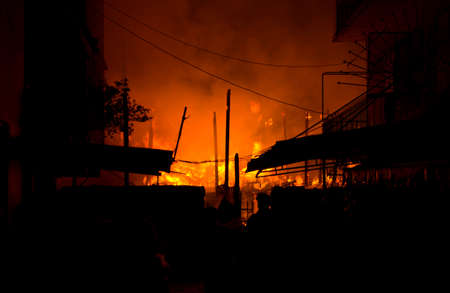 Houses, apartment, flat on fire and burning down at night in the market, slum, local center...