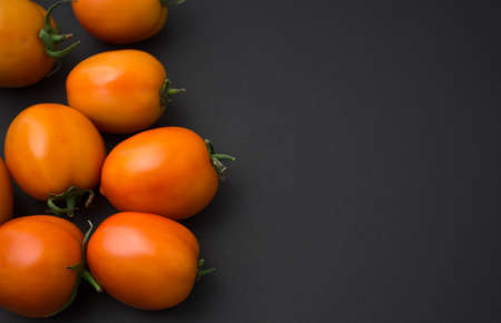 Tomatoes flat lay on black background. Tilted top view shot, horizontal, still life, food photography image style. Off-center composition, copy space for your text, image or design.の写真素材