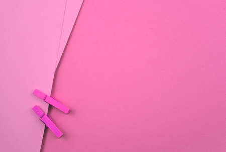 Pink pastel blank paper with wooden clips, pegs. Abstract minimal paper texture background. Free space for your text, image or design. Top view, horizontal image style.の写真素材