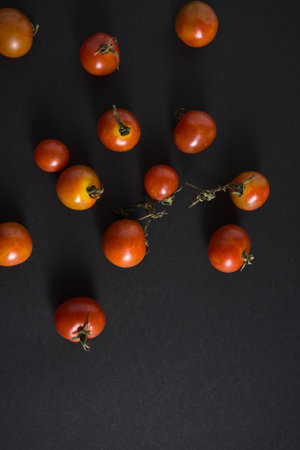 Cherry tomatoes flat lay on black grunge texture abstract background. Food, vegetables photography with space. Top view, vertical, neutral vintage moody image style.の写真素材