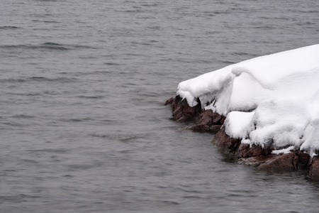 rock with snow on the coastの写真素材