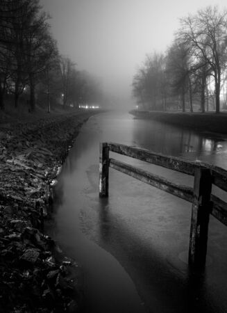black and white image of a canal in the fogの写真素材