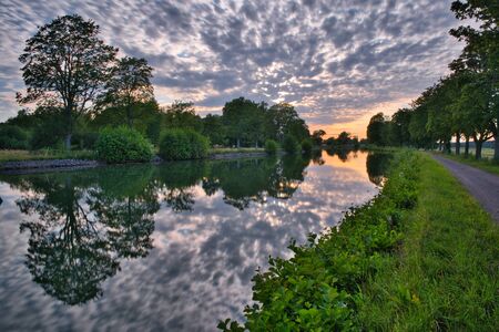Effective clouds at sunset reflecting in a canal