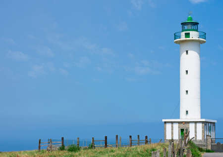 white lighthouse on sunny day with fenced fieldの写真素材