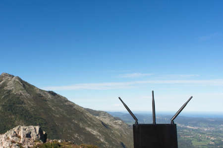 Black internet router on mountain with blue background reflecting the concept of connectivity everywhereの写真素材