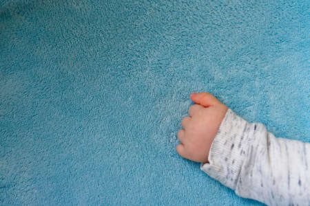 babys hand on a blue blanketの写真素材