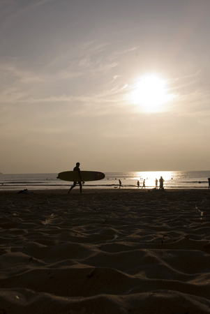 Silhouette of Night Surfer walking along the beach at sunsetの写真素材