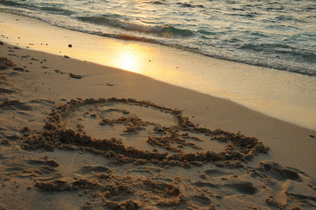 Heart Drawing in the sandwith Beautiful Golden Sunset or Sunrise over the Oceanの写真素材