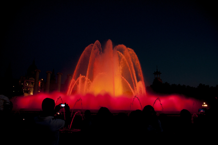 Silhouette of person taking a photo of a Large colourful Water Fountain displayの写真素材