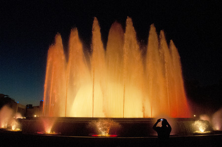 Silhouette of person taking a photo of a Large colourful Water Fountain displayの写真素材