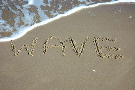 Wave on beach - written on sandの写真素材