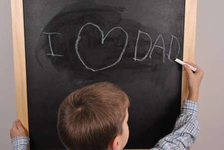 Young boy  writing on the blackboard his feelingの写真素材