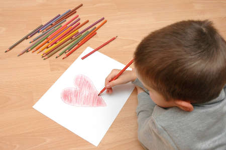 child draw heart on paper with crayonsの写真素材