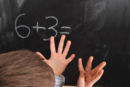 Junior pupil by the blackboard is solving mathematical problemsの写真素材