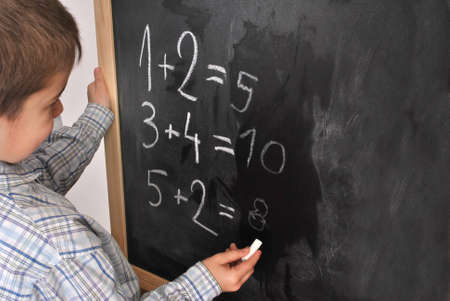 Junior pupil by the blackboard is solving mathematical problemsの写真素材