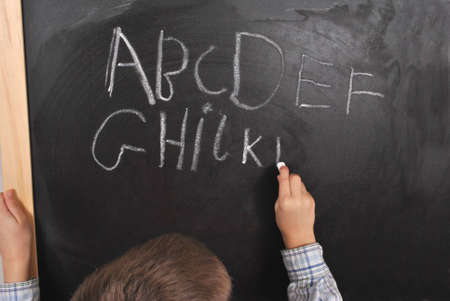 Fresh pupil is writing the alphabet on the blackboardの写真素材