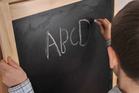 Fresh pupil is writing the alphabet on the blackboard