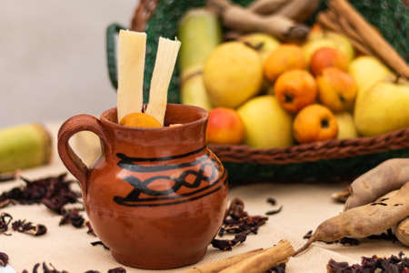 Jar of Christmas fruit punch with cane and tejocote. basket with apple, guava, cinnamon and tamarind fruits. On the table hibiscus leavesの写真素材