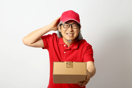 The Asian man dressed red polo shirt with red cap standing on the white background.の写真素材
