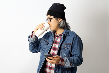 The Asian man with denim shirt and beanie standing on the white background.の写真素材