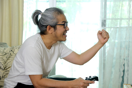 The Asian man playing game in the living room.の写真素材