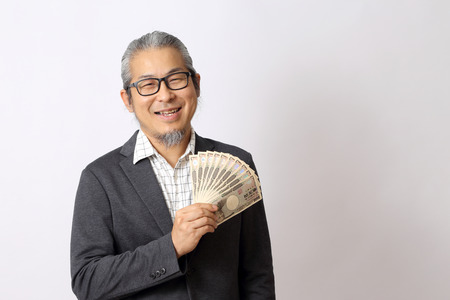 The Asian man holding money on the white background.の写真素材