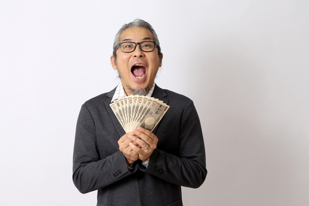 The Asian man holding money on the white background.の写真素材