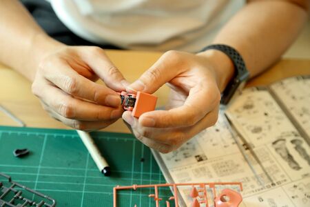 The Asian man doing on plastic model as his hobby.