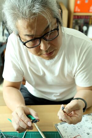 The Asian man doing on plastic model as his hobby.