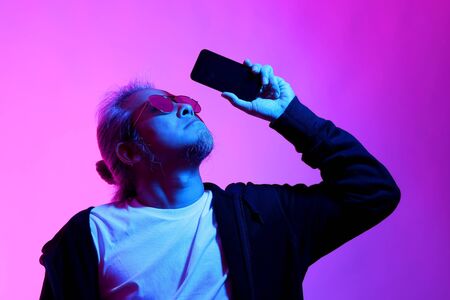 The Asian man posing on the white background with the gel color light.の写真素材