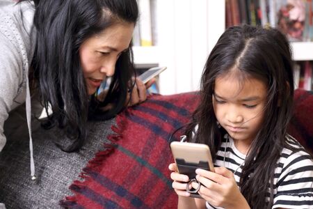 The Asian woman looking her child using smart phone.