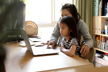 The Asian woman teaching her child to use computer.の写真素材