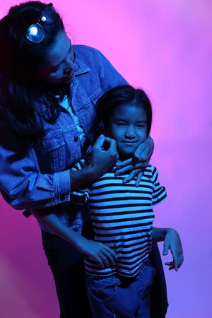 The Asian mother and daughter posing in the color gel light.の写真素材