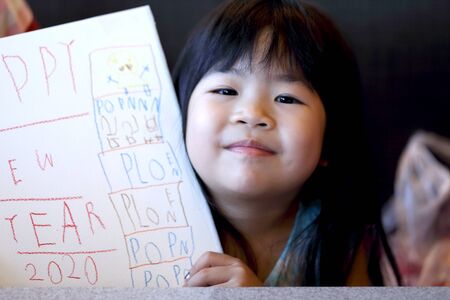 The Asian kid showing her artwork in the paper.