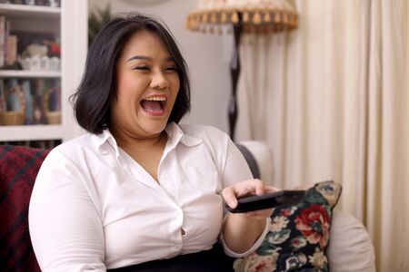The Asian woman relaxing in the livingroom.