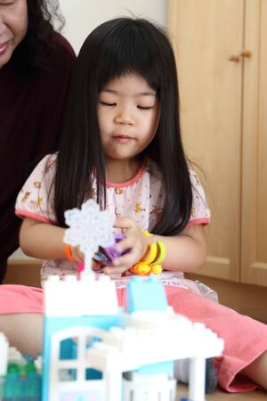 The Asian girl playing toy in the room.