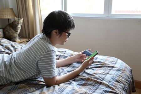 The Asian woman using smart phone on the bed.の写真素材