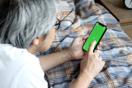 The Asian man using smart phone on the bed.の写真素材