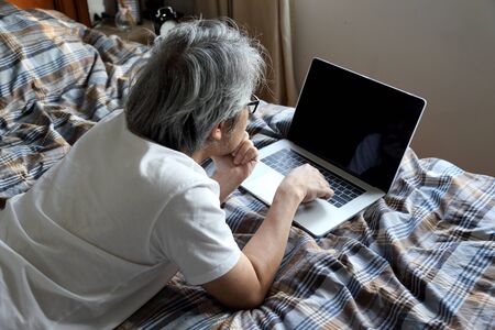 The Asian man using laptop on the bed.の写真素材