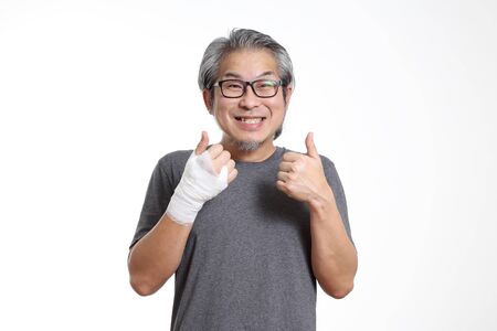 The Asian man with bandages on his hand standing on the white background.の写真素材